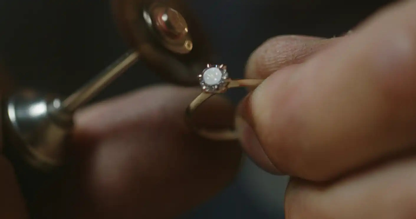 Close-up of a hand holding a diamond ring with a blurred background