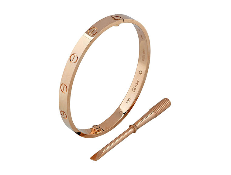 Rose gold cartier love bangle with a tool on a white background