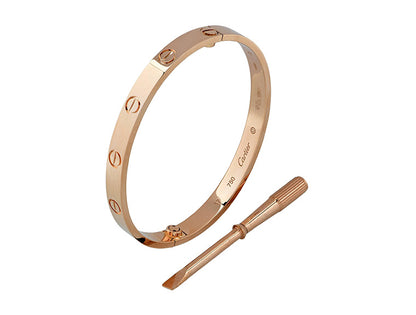 Rose gold cartier love bangle with a tool on a white background