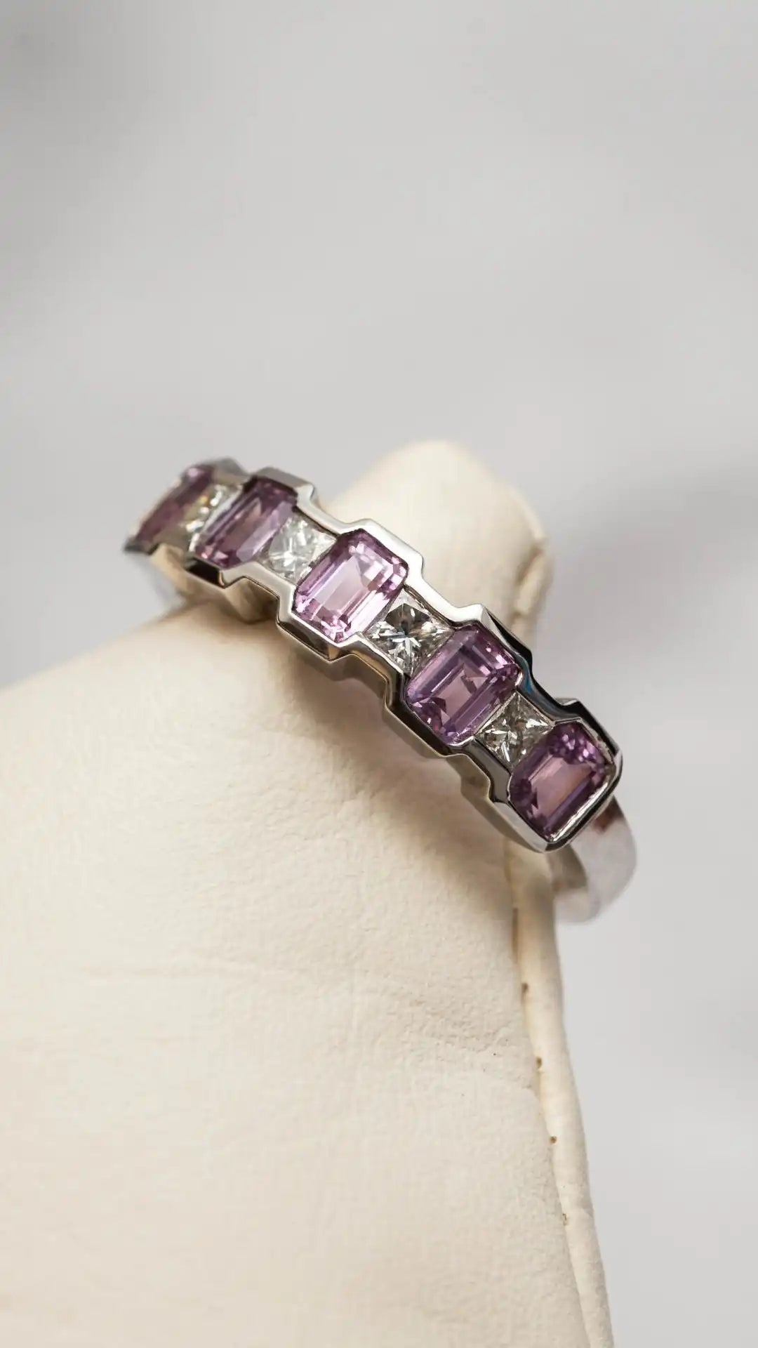 Platinum eternity ring with pink sapphire gemstones on a white background